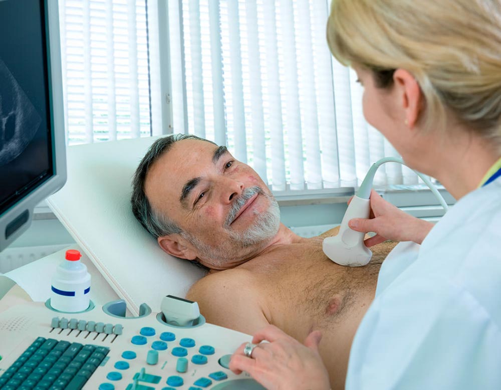 A doctor performing a chest ultrasound on a smiling elderly man.